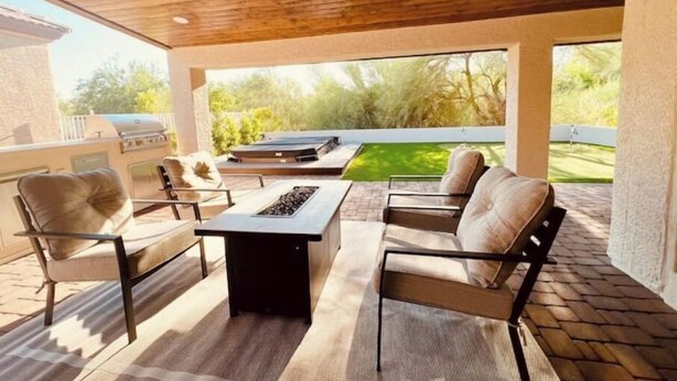 An outdoor patio with a ceiling fan, a grill, and a seating area with a fire pit. - Sun & Fun in Fountain Hills- HENDVR2 (Fountain Hills)