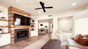 A modern living room with a fireplace, a ceiling fan, and a sofa. - Sun & Fun in Fountain Hills- HENDVR2 (Fountain Hills)