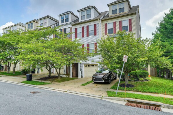 A townhouse with a garage, a driveway, and a car parked in front. - Owings Mills Townhouse: 8 Mi to Liberty Reservoir! (Owings Mills)