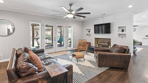 A modern living room with a fireplace, leather sofas, and a ceiling fan. - Spacious 7 Bedrooms w/ Huge Backyard Downtown ATL (Atlanta)