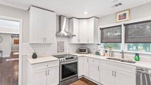 A modern kitchen with white cabinets, stainless steel appliances, and a window with blinds. - Spacious 7 Bedrooms w/ Huge Backyard Downtown ATL (Atlanta)