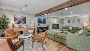 Un salon avec une cheminée, un canapé vert, des meubles en bois et un mur en pierre.