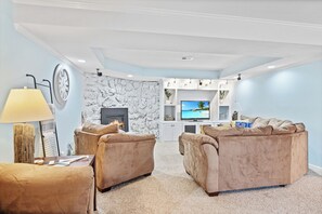 Relax in this stylish living room with a fireplace, flat-screen TV, and plush sofas.