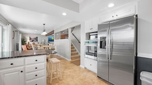 A modern kitchen with a stainless steel refrigerator, a built-in oven, and a water dispenser.
