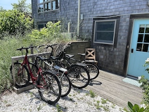 A wooden deck with bicycles parked on it, a wooden chair, and a blue door. - Hot Tub & Ocean Views from Deck (Provincetown)