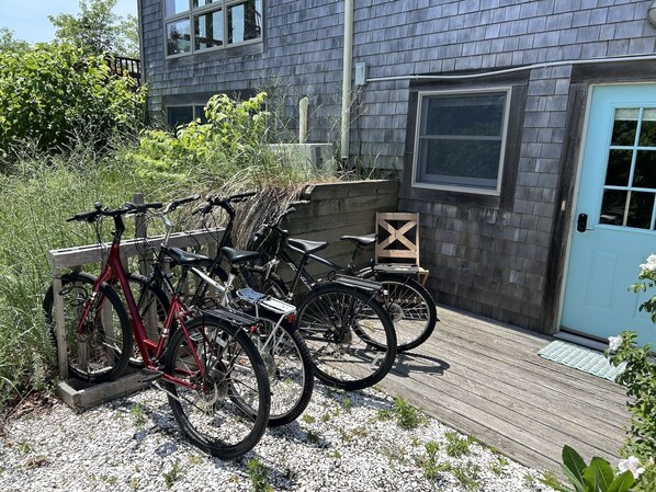 A wooden deck with bicycles parked on it, a wooden chair, and a blue door.