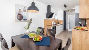 Eine moderne Küche mit Holzschränken, einem eingebauten Backofen und einem Essbereich mit einem dunklen Holztisch und Stühlen.