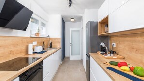 Eine moderne Küche mit weißen Schränken, einer Holz Arbeitsplatte, einem eingebauten Ofen und einem Kühlschrank.