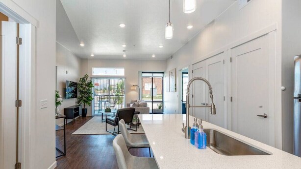 A modern kitchen with a large island, stainless steel appliances, and a dining area with a view. - Apartment 2103 · Luxury style 2 bed 2 bath apartment (North Salt Lake)