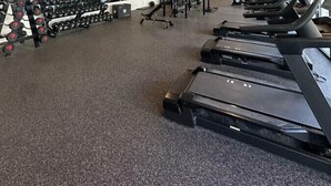 Un gimnasio espacioso con cintas de correr, mancuernas y máquinas de pesas.