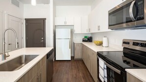 Eine moderne Küche mit Edelstahlgeräten, Holzschränken und einer zentralen Kochinsel.