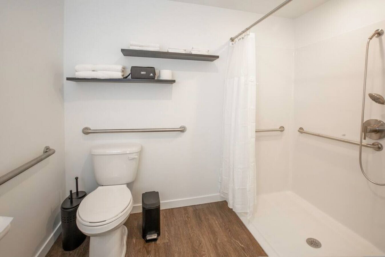 Un baño con inodoro, bidé, ducha con puerta de cristal y un perchero para toallas.