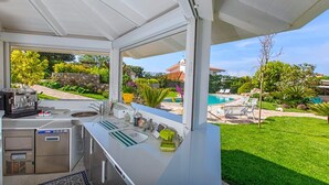 A kitchen with a view of a swimming pool and garden. - Resort Lubrense - Fiore Di Campo with shared pool (Sant'Agata Sui Due Golfi)