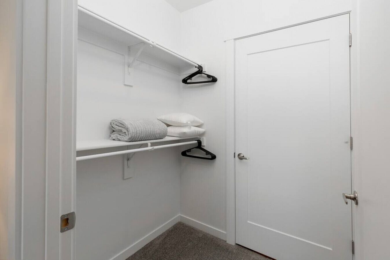 Un piccolo armadietto bianco con ripiani, una porta e un pavimento rivestito di moquette.