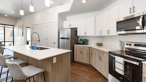 A modern kitchen with white cabinets, stainless steel appliances, and a central island with bar stools.