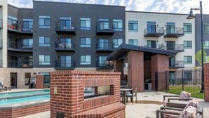 Un espace extérieur moderne, aménagé en terrasse, avec une cheminée en briques, des sièges et une piscine.