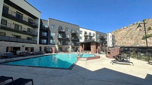 Un espace piscine avec des chaises longues et un bâtiment doté de nombreux balcons.