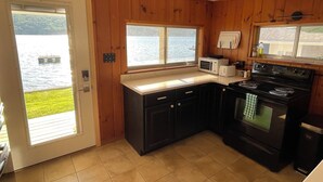 Une cuisine avec des murs en bois, un fourneau, un four à micro-ondes et une fenêtre donnant sur un lac.