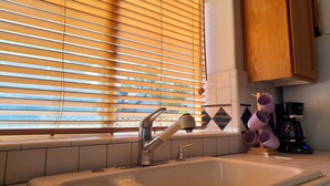 A kitchen with a sink, wooden cabinets, and a window with blinds. - Gresham House: Your home away from home... A comfy, cozy corner of Gresham.  (Gresham)