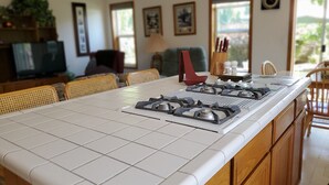 A kitchen with a large island, wooden cabinets, and a dining area with wicker chairs. - Gresham House: Your home away from home... A comfy, cozy corner of Gresham.  (Gresham)