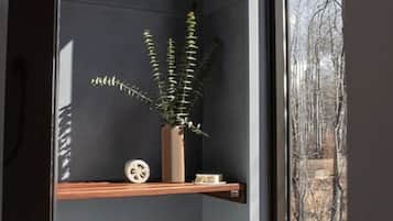 A corner room with a dark wall, a window, a wooden shelf, and a potted plant.