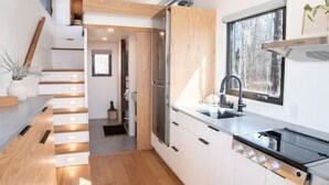 A modern kitchen with wooden flooring, white cabinetry, and a built-in stove.