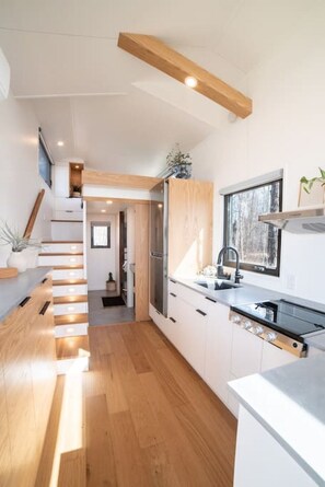 Eine moderne Küche mit Holzboden, weißen Schränken und einem eingebauten Backofen.