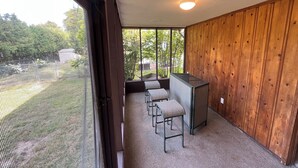 A room with a large window, a wooden wall, a small table, and a chair.
