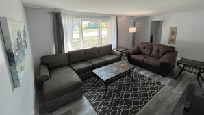 A living room with a sectional sofa, a smaller sofa, a coffee table, and a patterned rug.