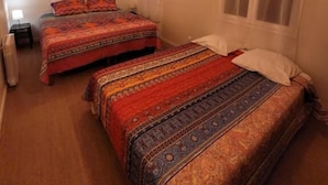 Un dormitorio con dos camas, una ventana con cortinas y una lámpara colgante.