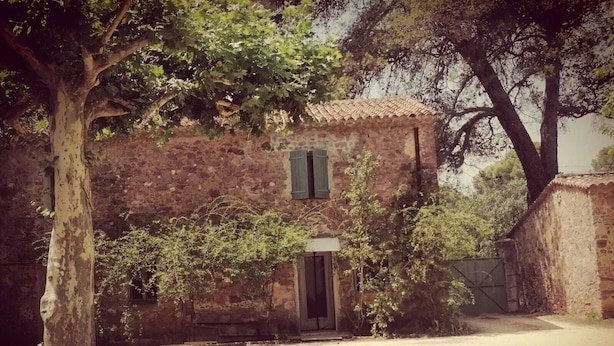 Un edificio rústico de piedra con un camino de tierra que lleva a una puerta de madera.