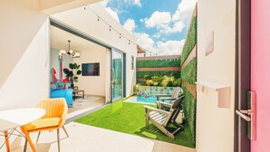 A modern outdoor patio with a pool, a dining area with a table and chairs, and a green wall with plants. - Privada Stays - Private Pools & Colorful-Chic Boutique Hotel - Adults Only (Oranjestad)