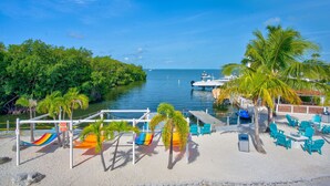 A beachside area with a pool, palm trees, and a dock. - Key Largo Home 3 Bed/3 Bath (Key Largo)