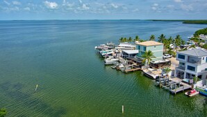 A marina with boats docked, a building with a light blue roof, and palm trees. - Key Largo Home 3 Bed/3 Bath (Key Largo)