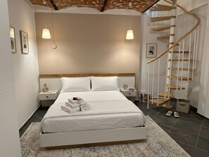 Un dormitorio moderno con una cama grande, una escalera en espiral y un diseño minimalista.