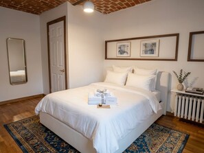 Habitació d'hotel amb un llit gran, una taula de nit amb un vas i un radiador.