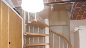 Eine Wendeltreppe mit Holzstufen und weißen Geländern, die zu einer höheren Etage führt.