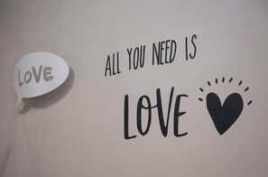 Un mur sur lequel est écrit « TOUT CE DONT VOUS AVEZ BESOIN, C’EST L’AMOUR », et une bulle de dialogue contenant le mot « AMOUR ».