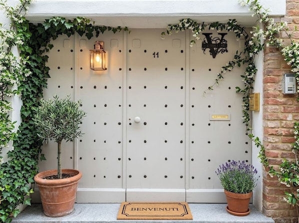A white door with a number '11' and a 'LETTER' sign, surrounded by greenery and a potted plant.