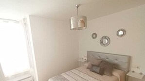 A bedroom with a bed, bedside tables, a hanging light fixture, and decorative wall mirrors. - Paraiso del sol (Fuengirola)
