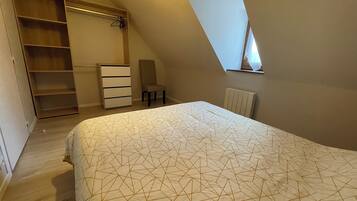 Een slaapkamer met een bed, een dressoir, een stoel en een inloopkast.