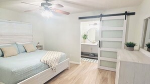 A bedroom with a bed, a ceiling fan, a dresser, and a sliding barn door. - 3 bedroom house in Crystal River
 (Crystal River)