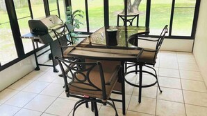 A dining area with a glass table and chairs, a grill, and a view of a grassy yard through large windows. - 3 bedroom house in Crystal River
 (Crystal River)