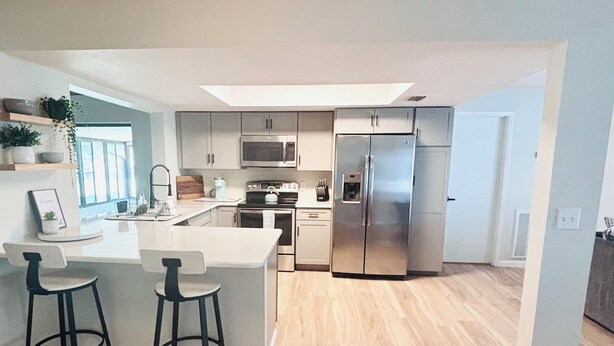 A modern kitchen with a central island, stainless steel appliances, and light wood flooring. - 3 bedroom house in Crystal River
 (Crystal River)
