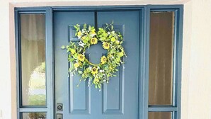 A blue front door with a wreath, a doormat with "Welcome to Our Home" text, and a window with a view. - 3 bedroom house in Crystal River
 (Crystal River)