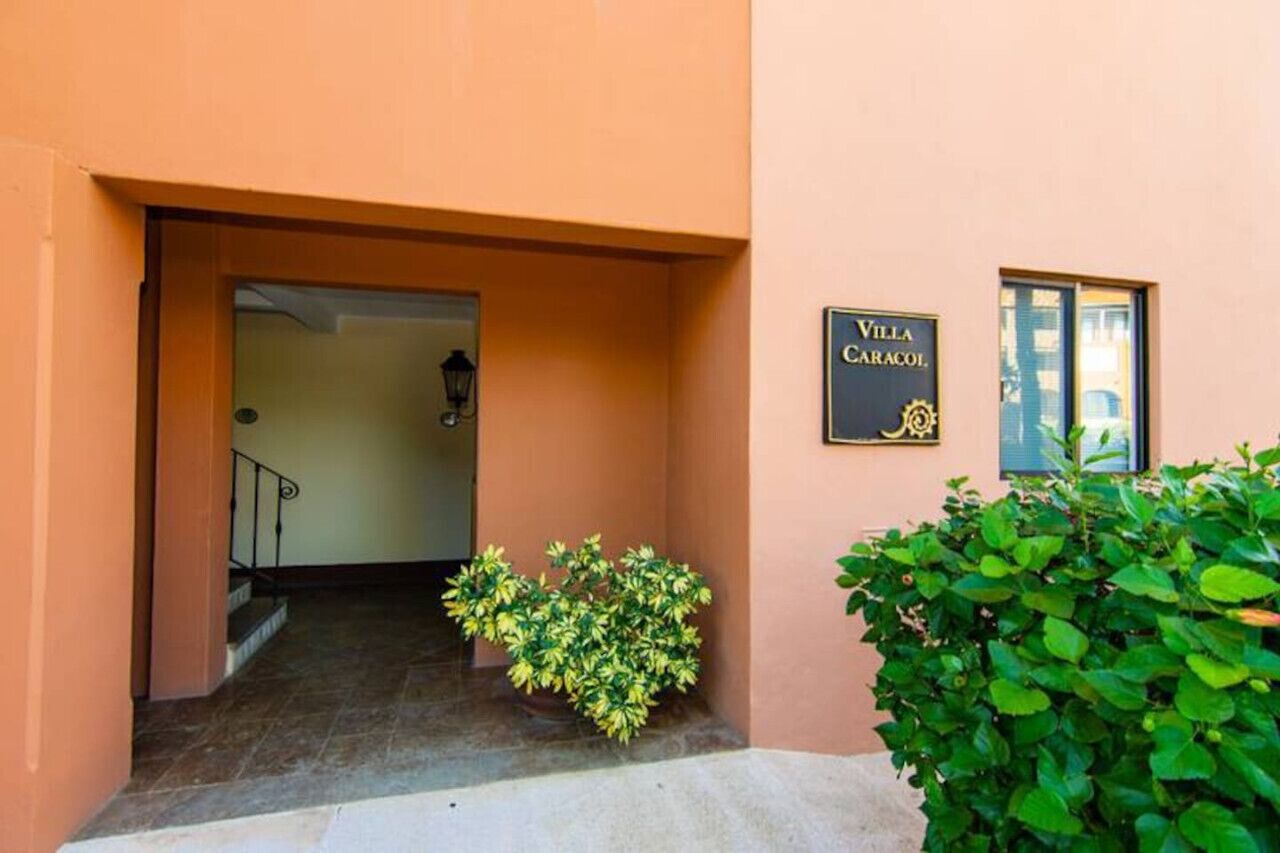An entrance to Villa Caracol with a sign, a staircase, and a small garden area.