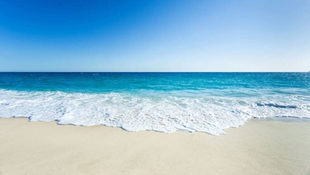 Una playa con agua azul cristalina y una orilla arenosa.