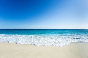 Ein Strand mit klarem, blauem Wasser und sandigem Ufer.