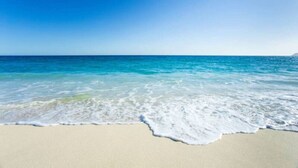 Ein Strand mit klarem, blauem Wasser und einem sandigen Ufer.