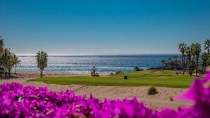 Ein Golfplatz mit freiem Blick auf das Meer und Palmen.